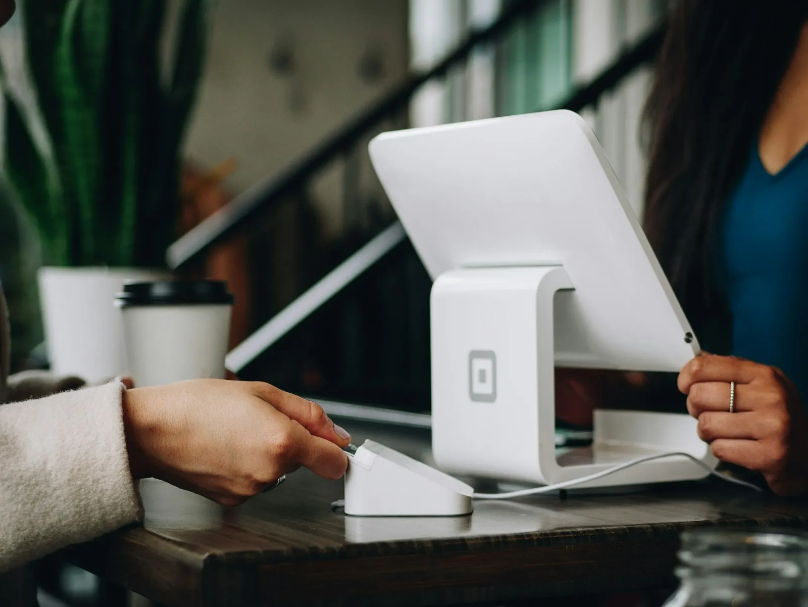 Empreendedora atendendo um cliente em seu pequeno negócio com terminal de pagamento