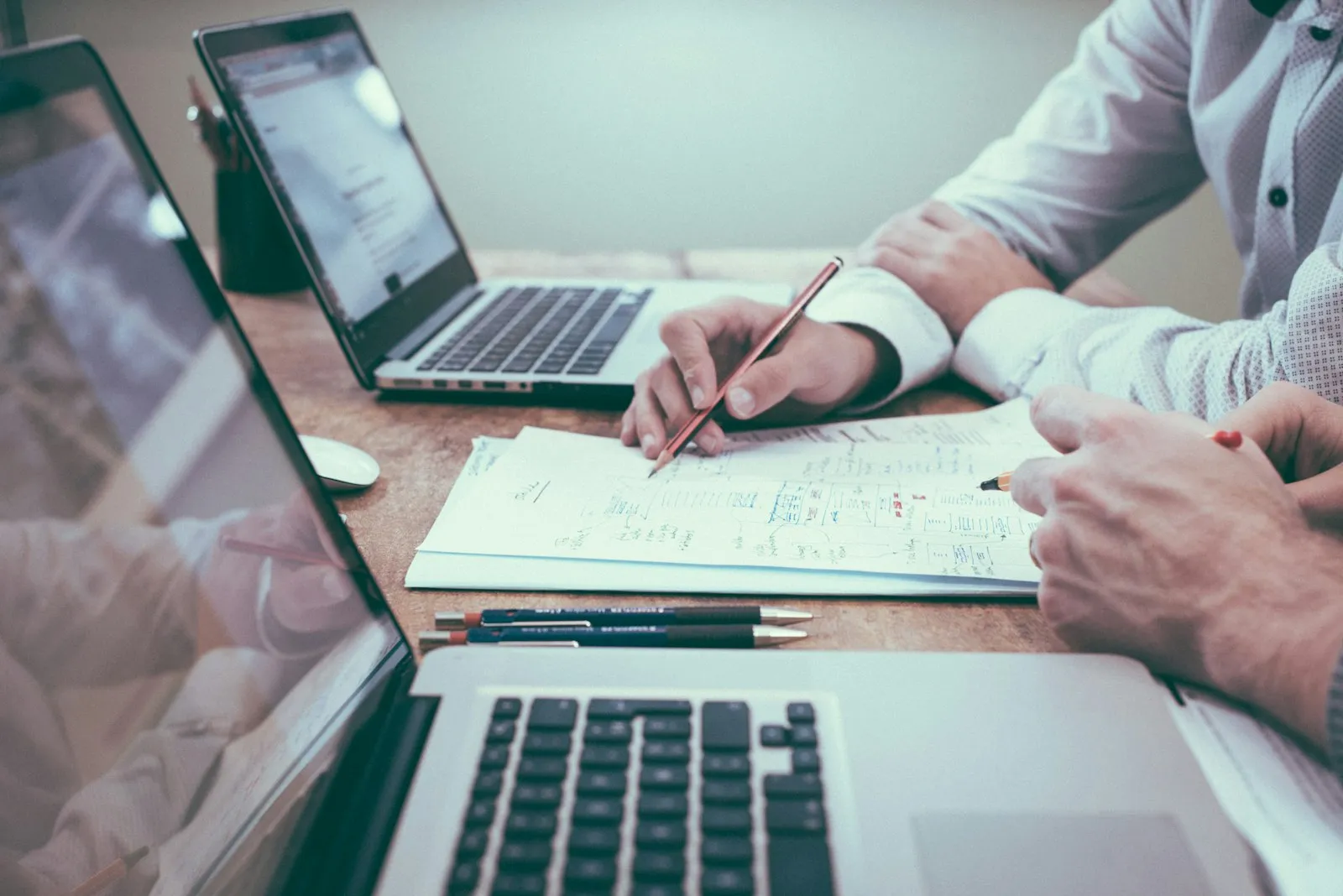 Dois profissionais analisando relatórios e gráficos financeiros sobre a mesa
